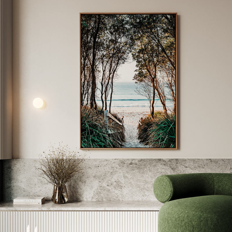 Framed artwork of a beach scene with trees on a wall above a green sofa.