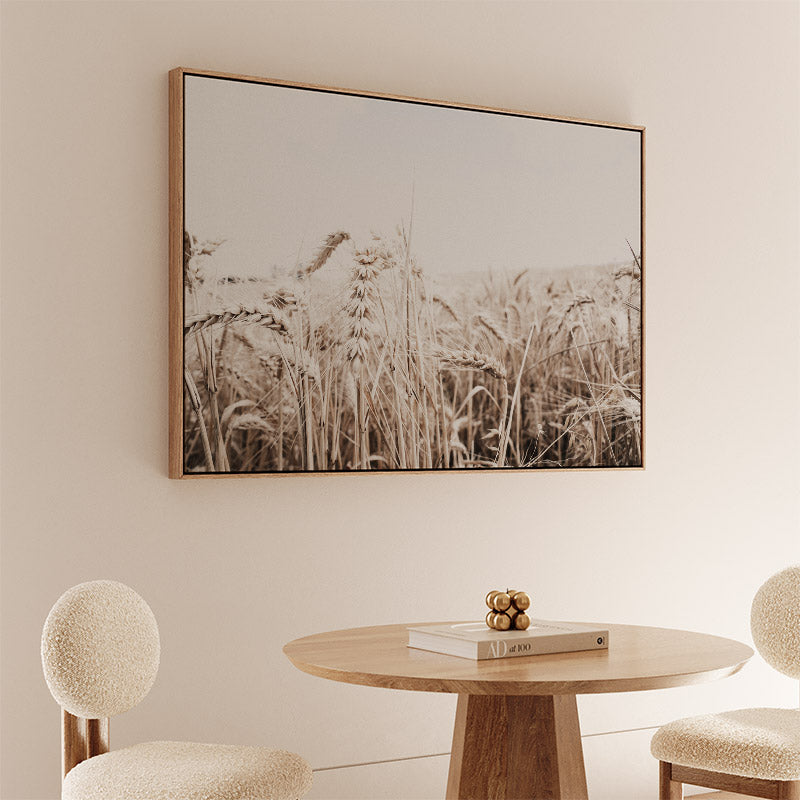 Round wooden table with decorative items in a room with a large framed landscape painting on the wall.