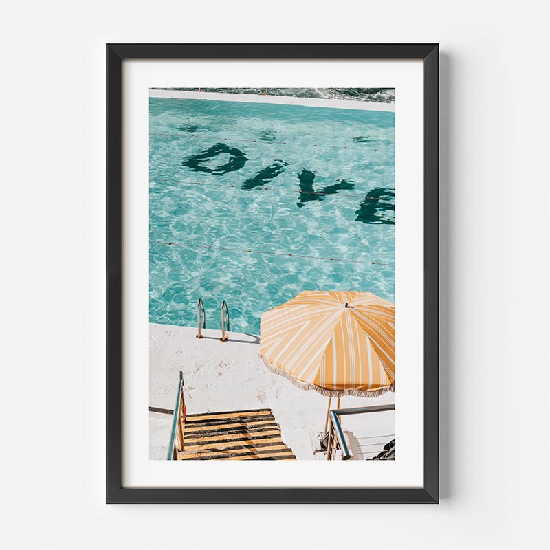Framed artwork of a beach scene with 'DIVE' text in clear water, yellow umbrella, and lounge chairs.