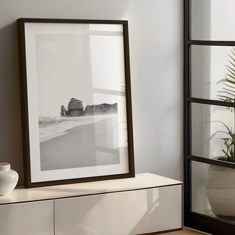 Framed black and white artwork on a wall next to a modern cabinet.