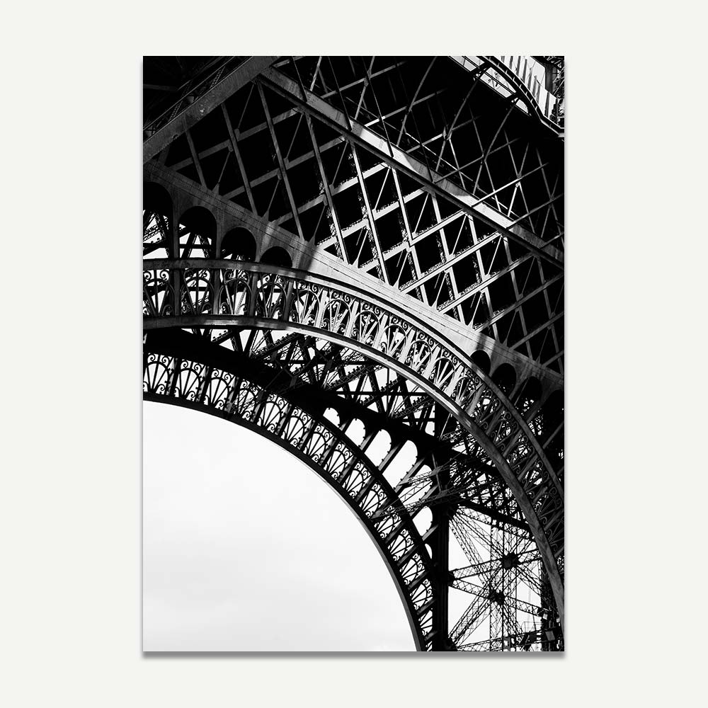 A black and white close-up photograph of the Eiffel Tower, focusing on its intricate ironwork and structure.