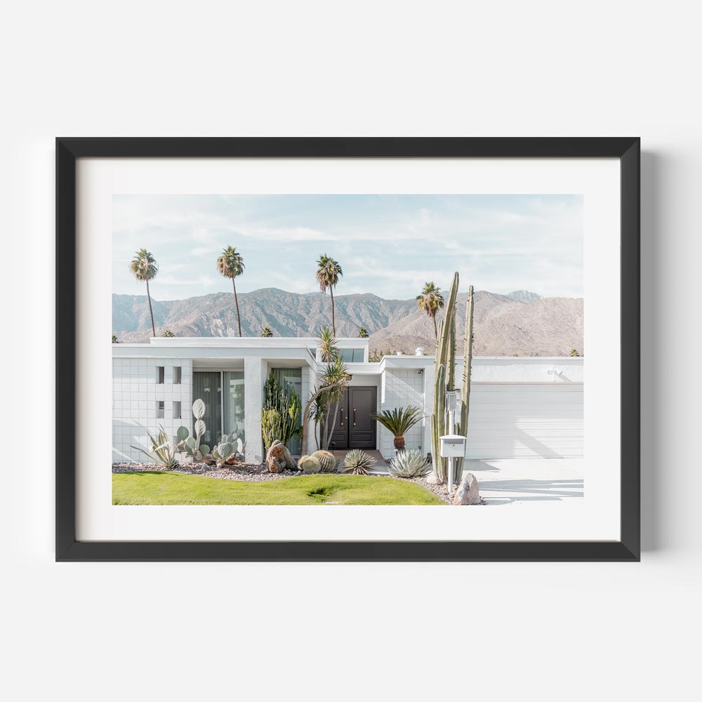 Framed photograph of a modern house with palm trees and mountains in the background