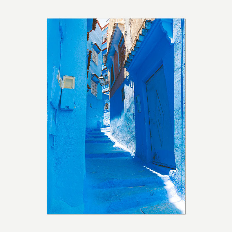 Narrow blue alleyway with vibrant blue walls and a door.
