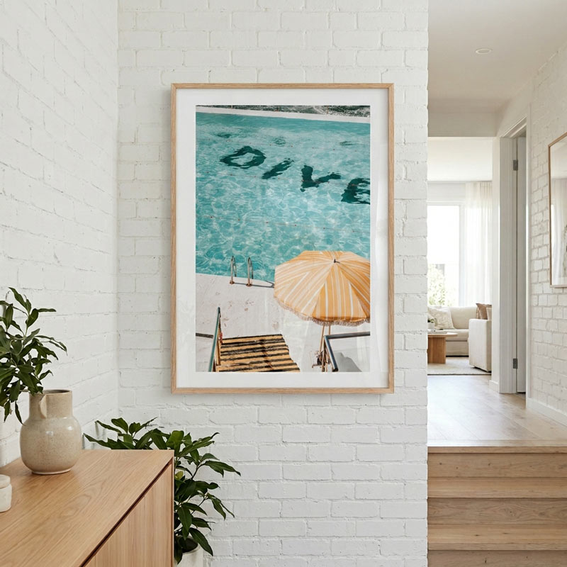 Framed artwork with 'DIVE' text on a white brick wall in a modern interior setting.