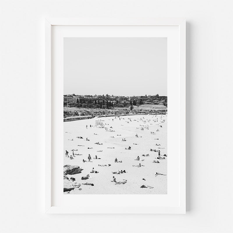 Framed black and white beach scene with people on a sandy shore.