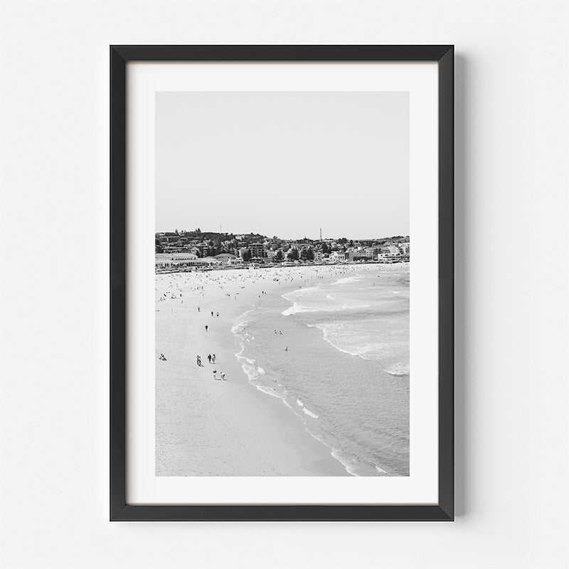 Framed black and white beach scene with people on the sand.