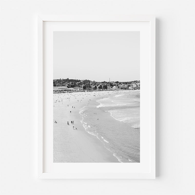 Framed black and white beach scene with people on the sand.
