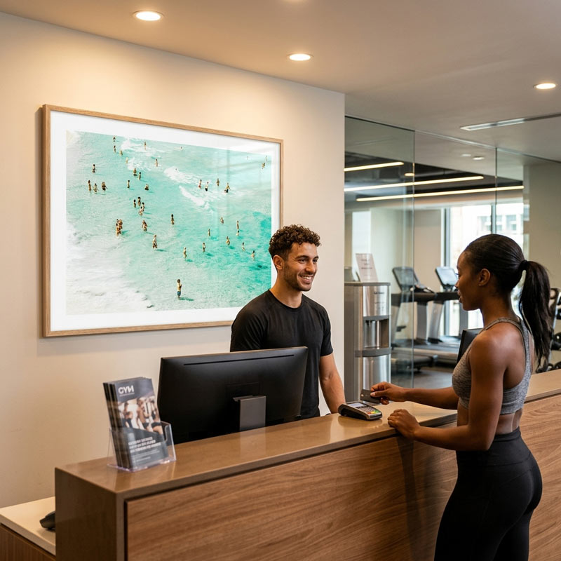 Person at a reception desk with a large framed artwork on the wall