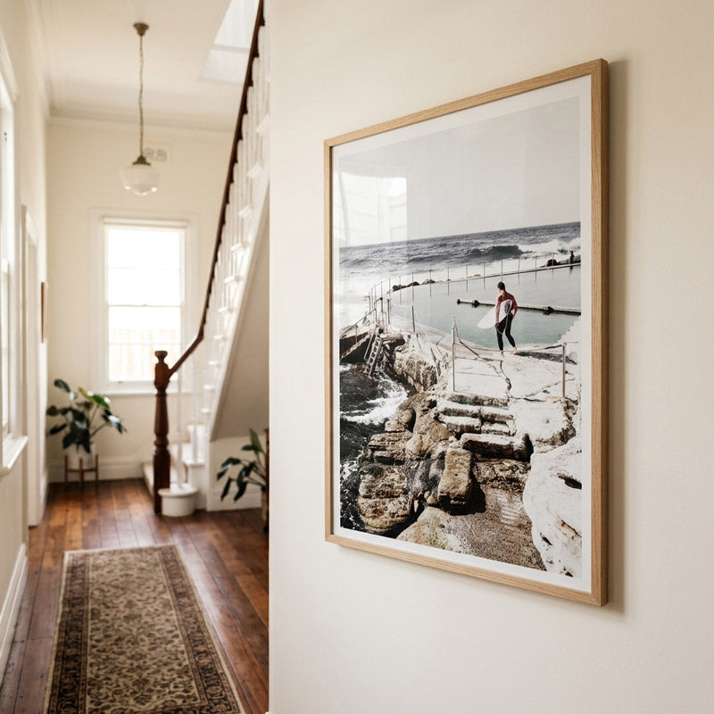 Framed photograph of a person on a rocky shoreline in a home hallway.