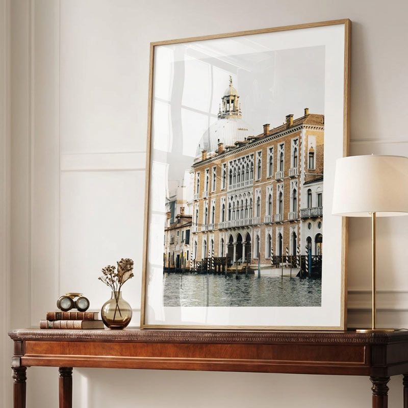 A large framed art print of a Venetian canal scene with historic buildings, displayed on a wooden console table in a styled room setting next to a lamp.
Venice, Italy: Ca' Foscari captured in stunning detail - Perfect for canvas prints and fine arts.