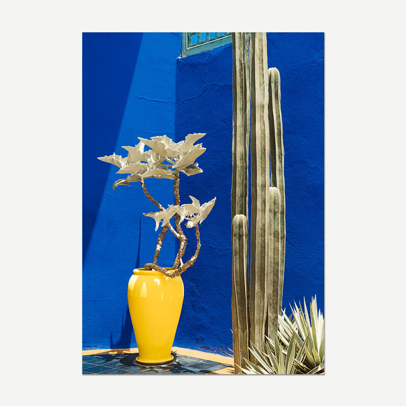 Yellow vase with a plant against a blue wall
