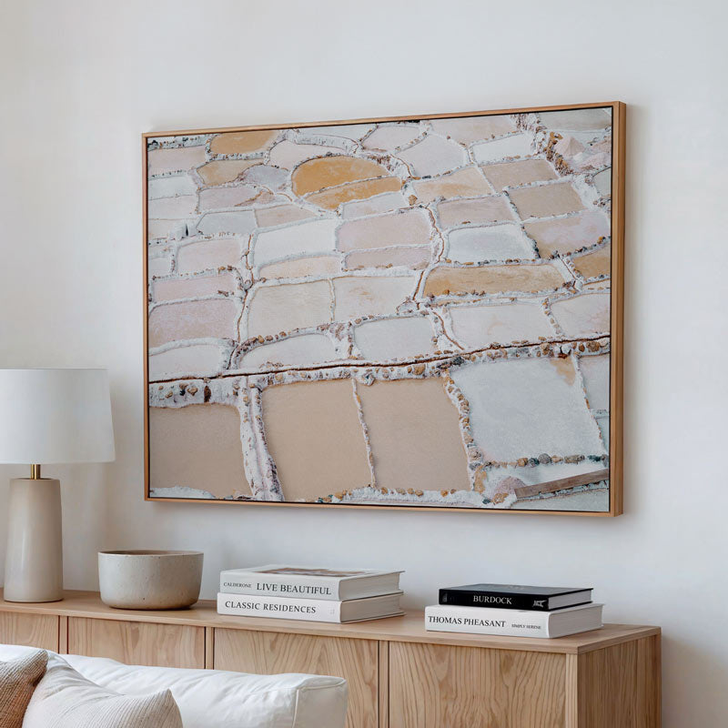 Abstract art piece on a wall above a wooden cabinet with books and decor items.