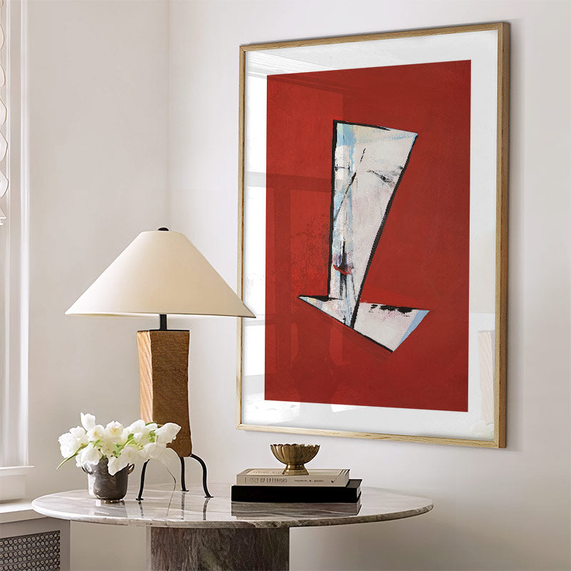 Abstract art piece on a wall with a lamp and decorative items on a table below.