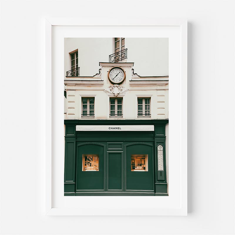 A green and white framed photo of a building with a clock, showcasing the iconic Chanel building in Paris, France.