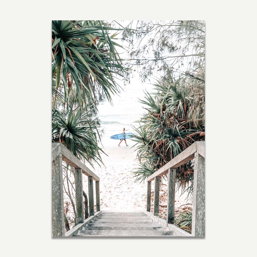 Surfer captured walking at Wategos Beach stairs in Byron Bay, framed by lush greenery and coastal scenery, front room wall art.