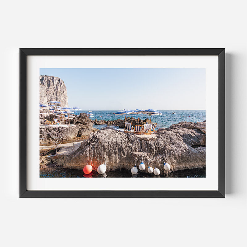 Framed photograph of a coastal scene with rocky outcrops and water.