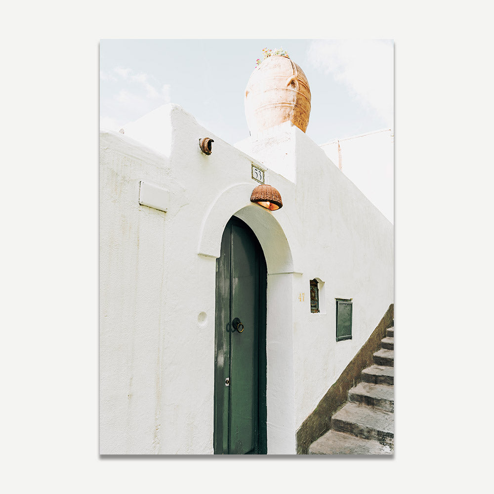 Green door framed by whitewashed Positano walls and rustic roof pot in this unique coastal wall art photograph.