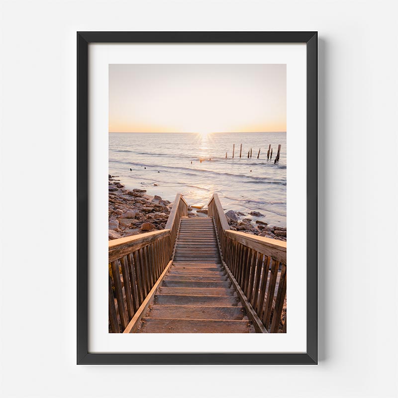 Framed photograph of a wooden staircase leading to a beach at sunset.