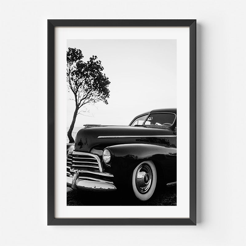 Framed black and white photograph of a classic car with a tree in the background.