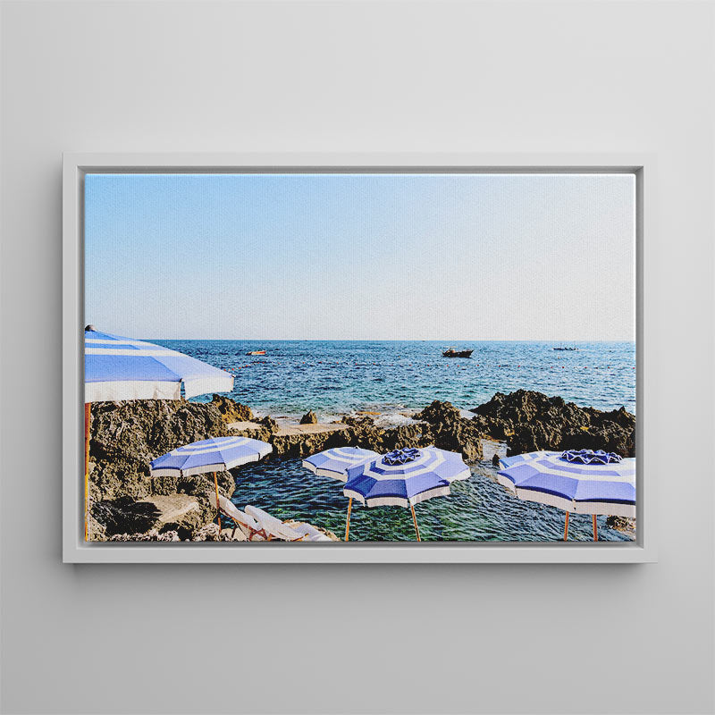 Framed photograph of blue umbrellas by the ocean on a gray wall