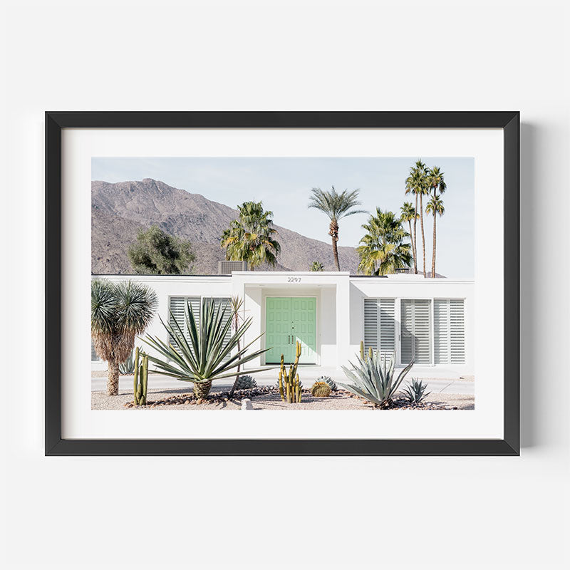 Framed photograph of a desert house with palm trees and mountains.