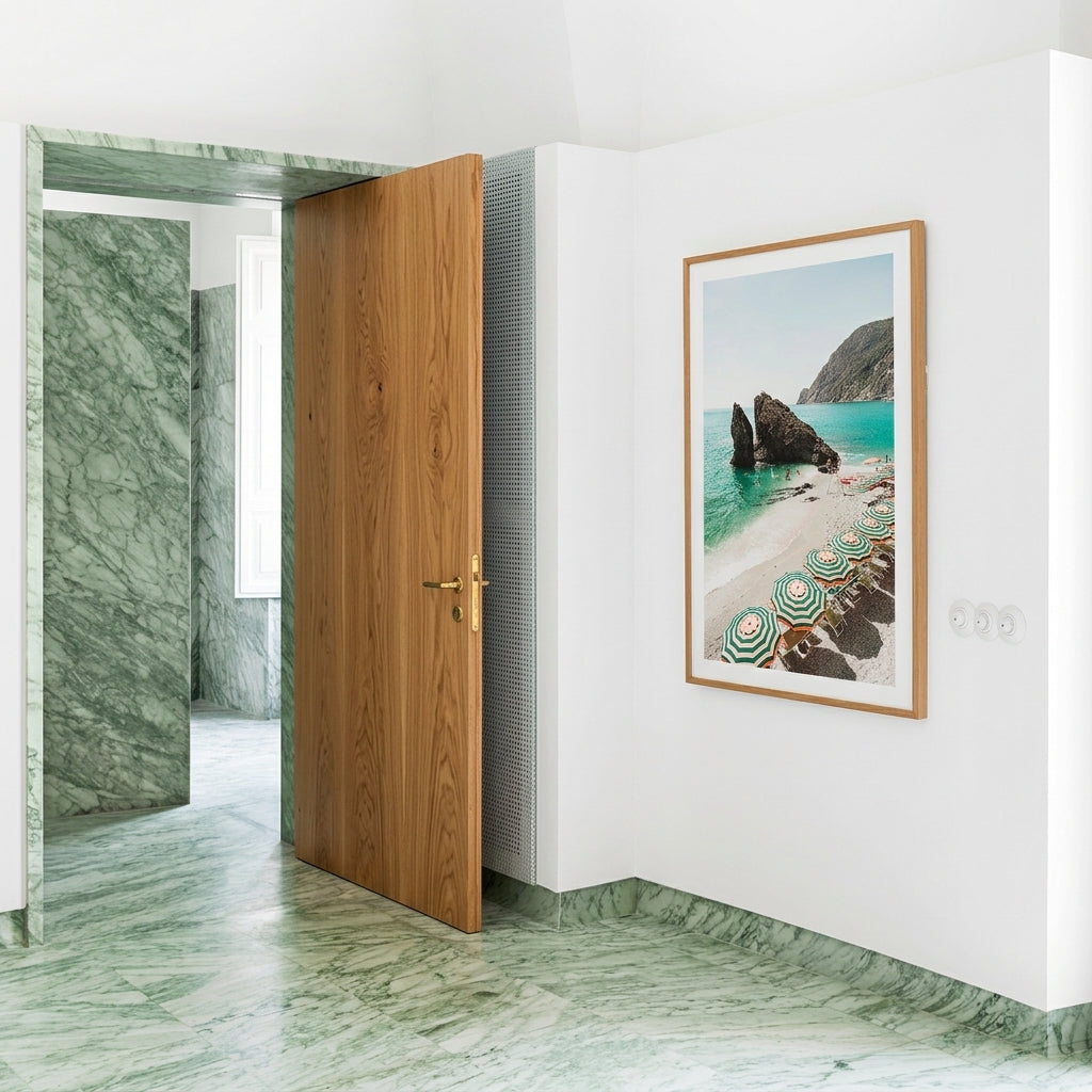 Wooden door in a room with marble walls and floor, framed artwork on the wall.
