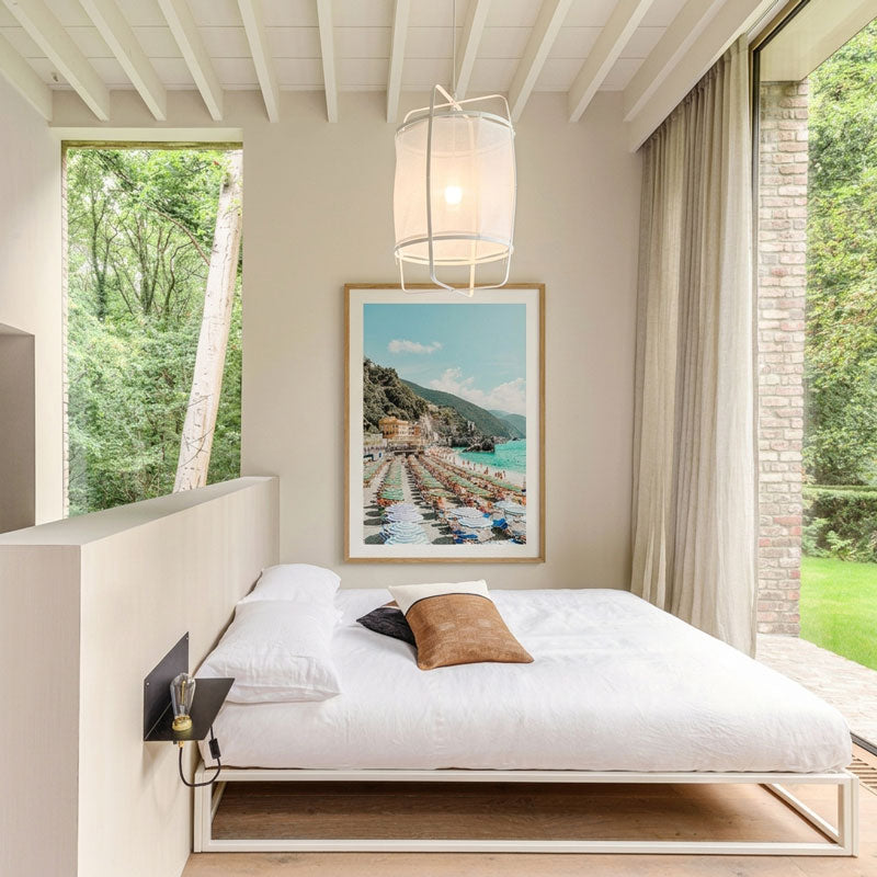 Modern bedroom with a large bed, framed picture on the wall, and large windows.