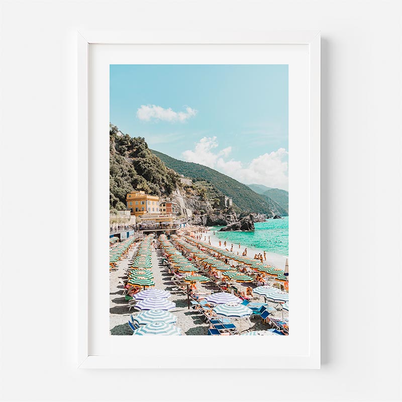Framed photograph of a beach scene with umbrellas and buildings.