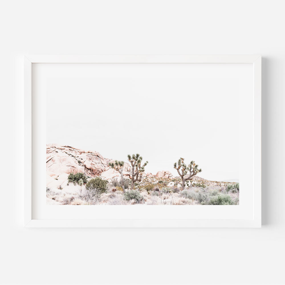 A framed artwork featuring a landscape photograph of Joshua trees in a desert setting with mountains in the background.