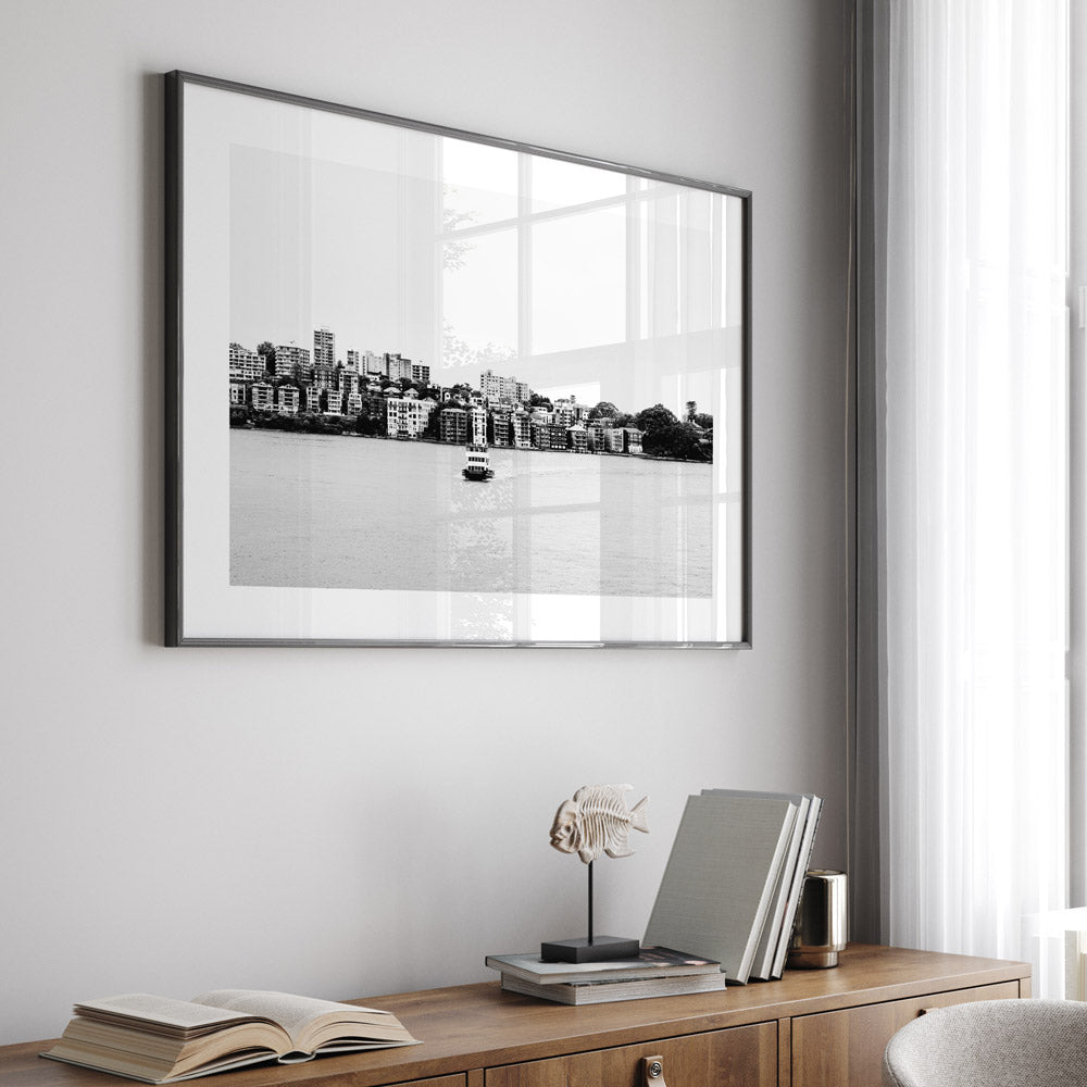 Black-and-white print of the ocean with distant buildings and a boat, evoking a serene yet dramatic atmosphere.
