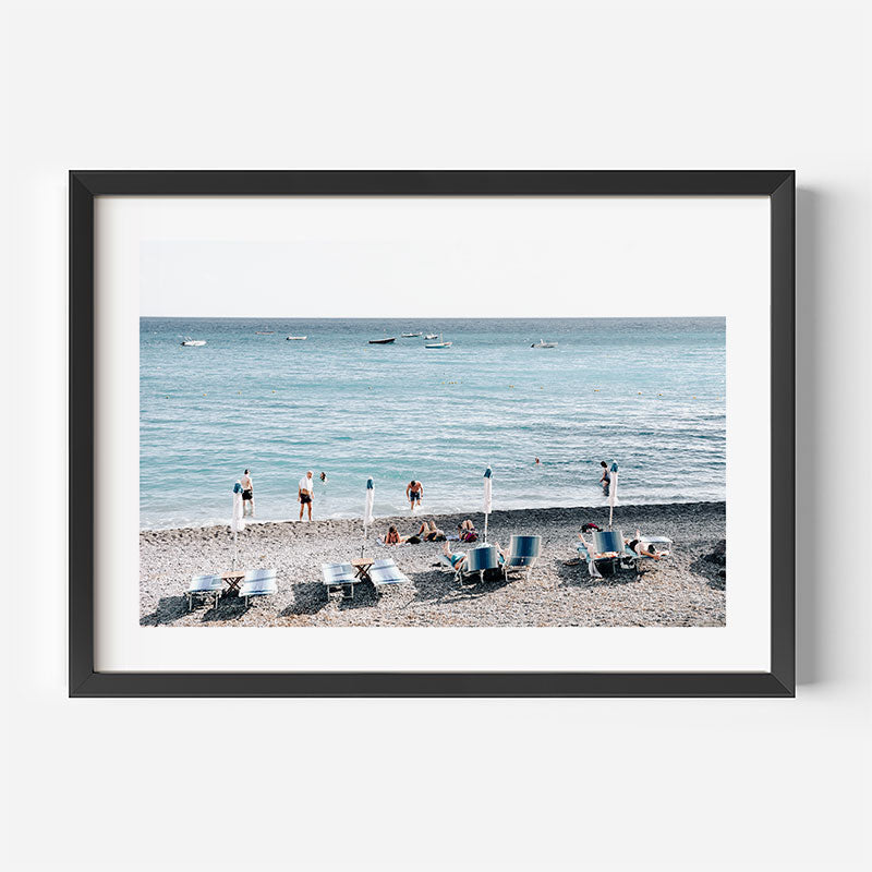 Framed photograph of a beach scene with people and lounge chairs.