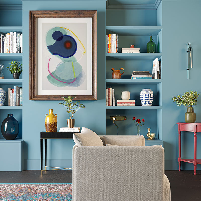 Living room with blue walls, a gray sofa, and decorative shelves.