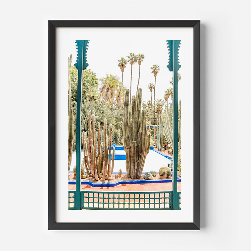Framed artwork of a cactus garden with a window frame design on a white wall.