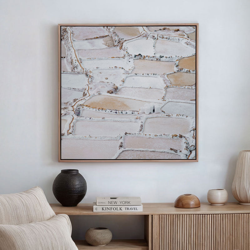 Abstract art piece on a wall above a wooden console table with decorative items.
