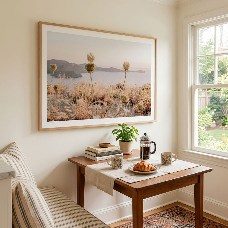 Nook with a wooden table, striped chair, and framed landscape painting.