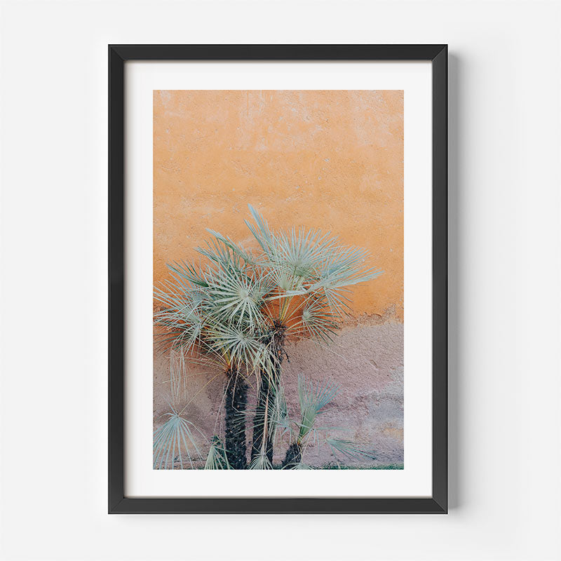 Framed artwork of a palm tree against an orange and pink gradient background