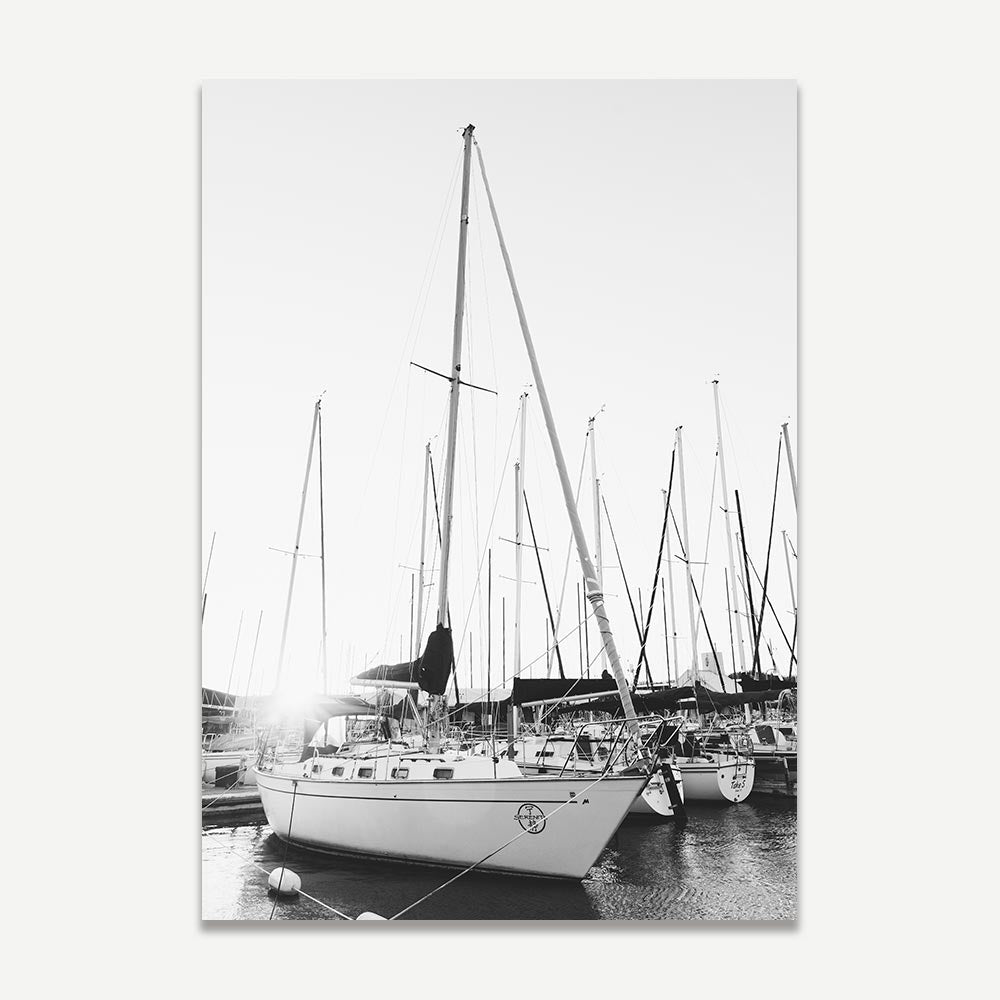 Black and white photograph of a yacht in a marina, with multiple masts visible in the background.