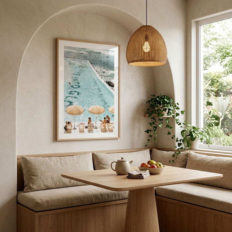Nook with a wooden table, cushioned bench, and framed beach scene on the wall.