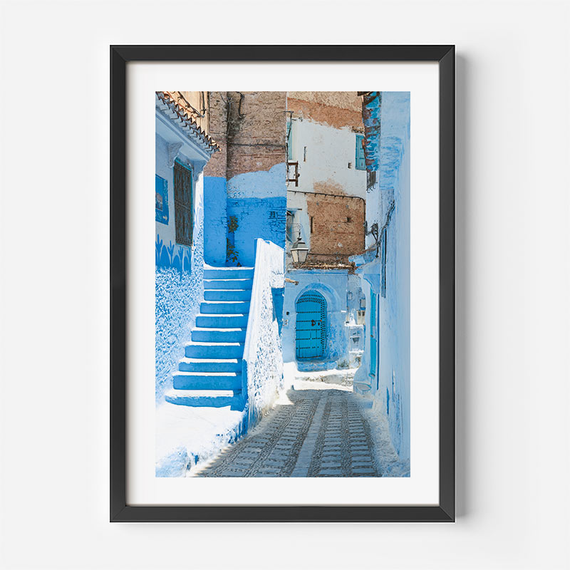 Framed artwork of a blue street scene with buildings and steps.