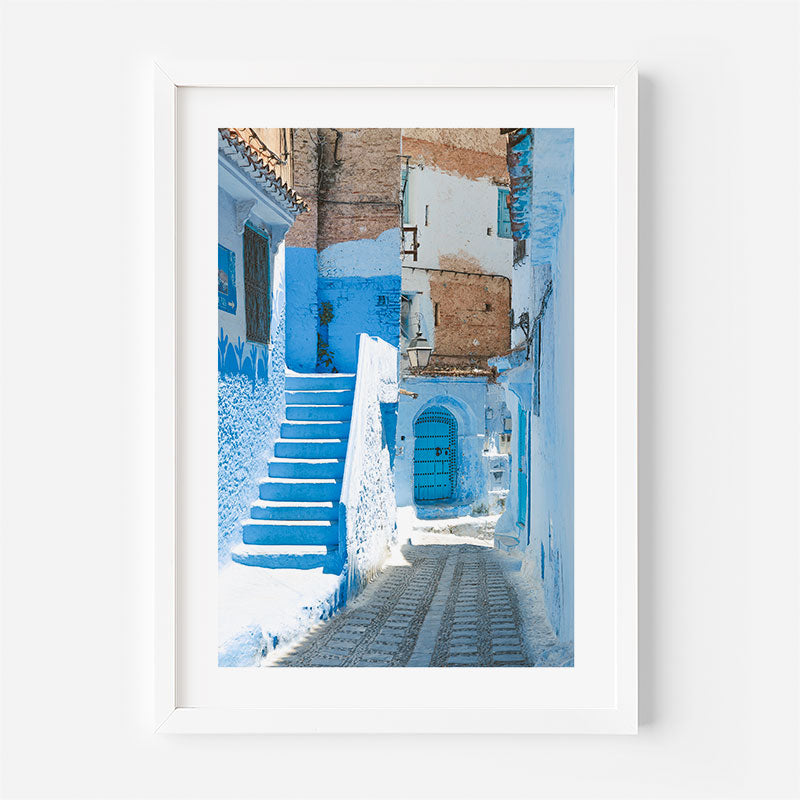 Framed photograph of a blue and white alleyway with steps in a cityscape.