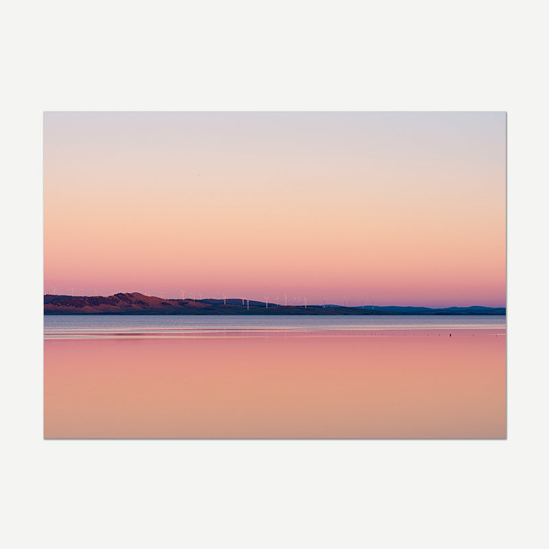Surreal landscape with pink and purple hues over water and mountains