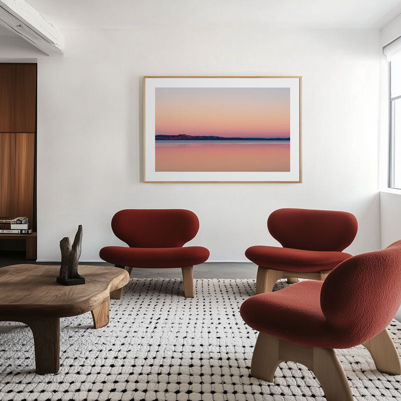 Modern living room with red chairs, wooden coffee table, and a framed artwork on the wall.