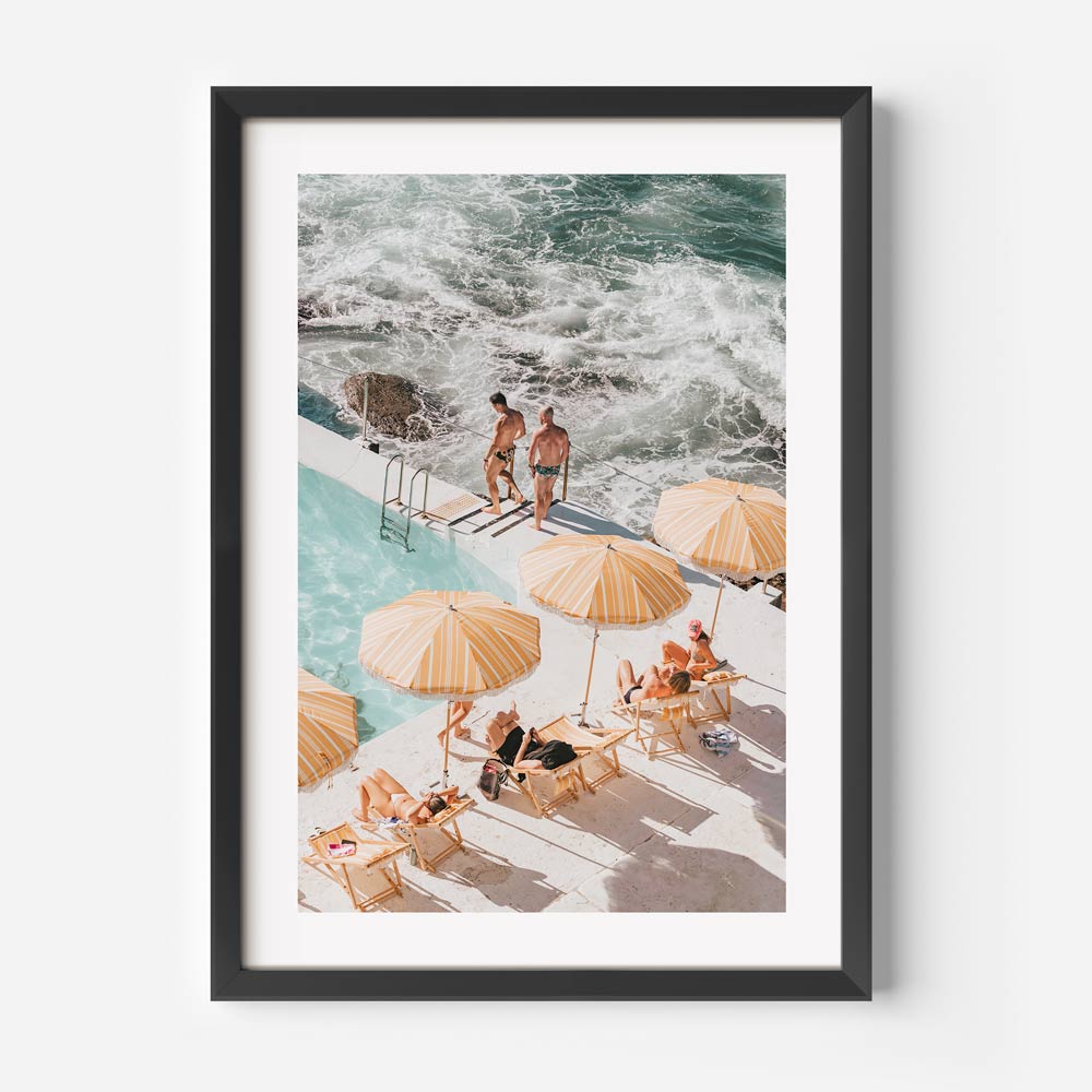 Black framed Vibrant beach wall art featuring yellow and white umbrellas at Bondi Icebergs ocean pool in summer