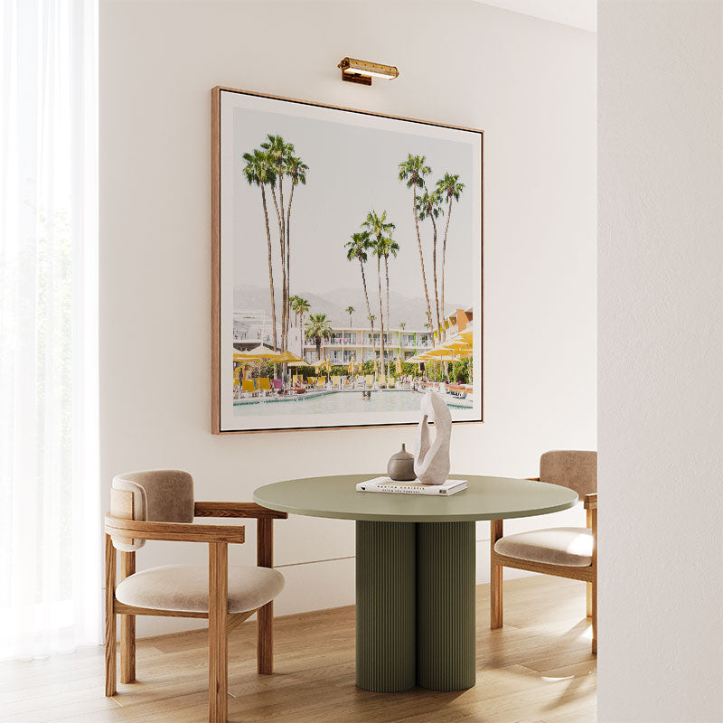 Dining room with a green table and chairs, framed artwork on the wall.