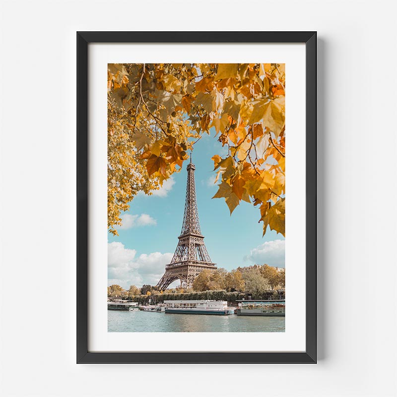 Framed print of the Eiffel Tower with autumn leaves on a white wall