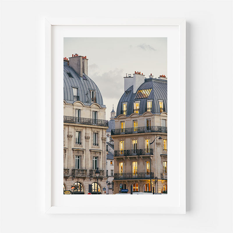 Framed photograph of Parisian buildings with lights on, on a white background