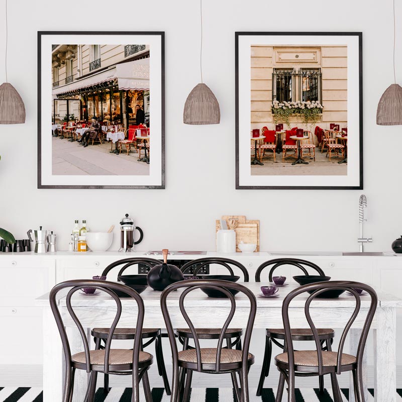 Dining room with a table and chairs, featuring framed pictures of outdoor café scenes on the wall.