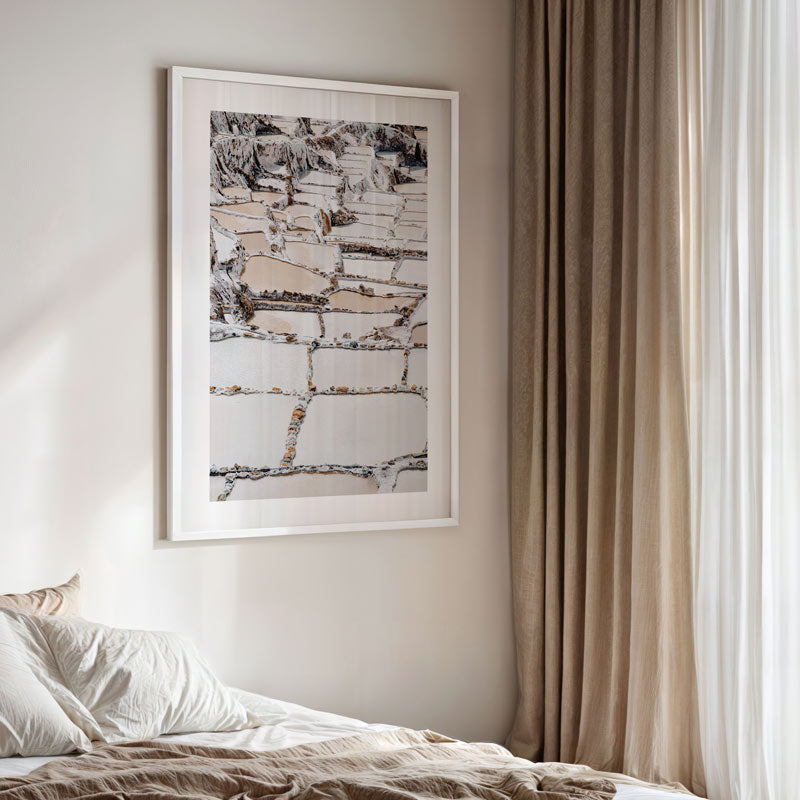 Framed abstract art on a wall above a bed with neutral tones.
