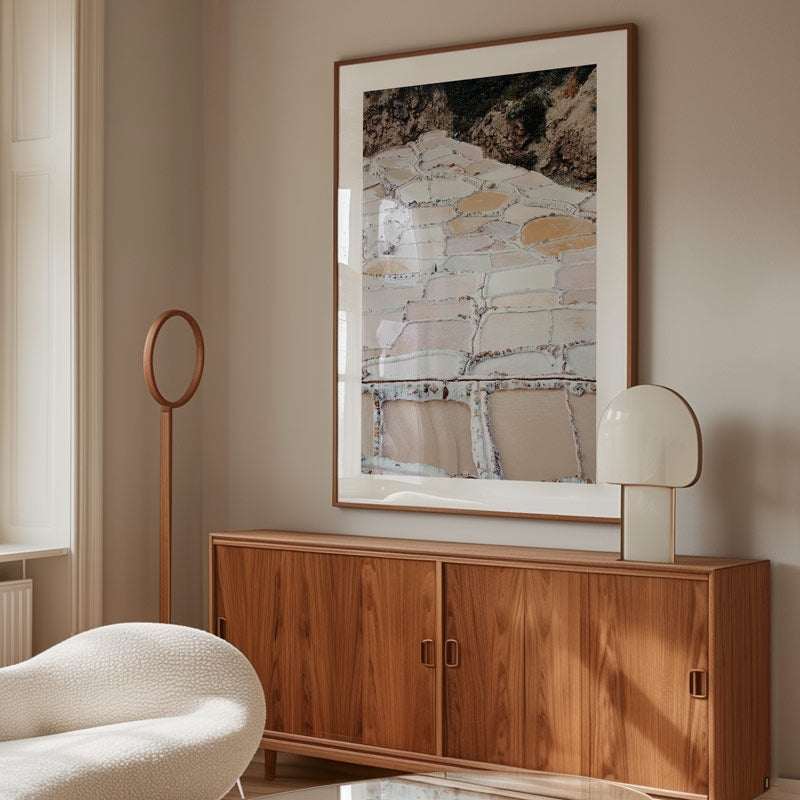 Wooden sideboard with a large abstract painting above it in a room with a chair and lamp.