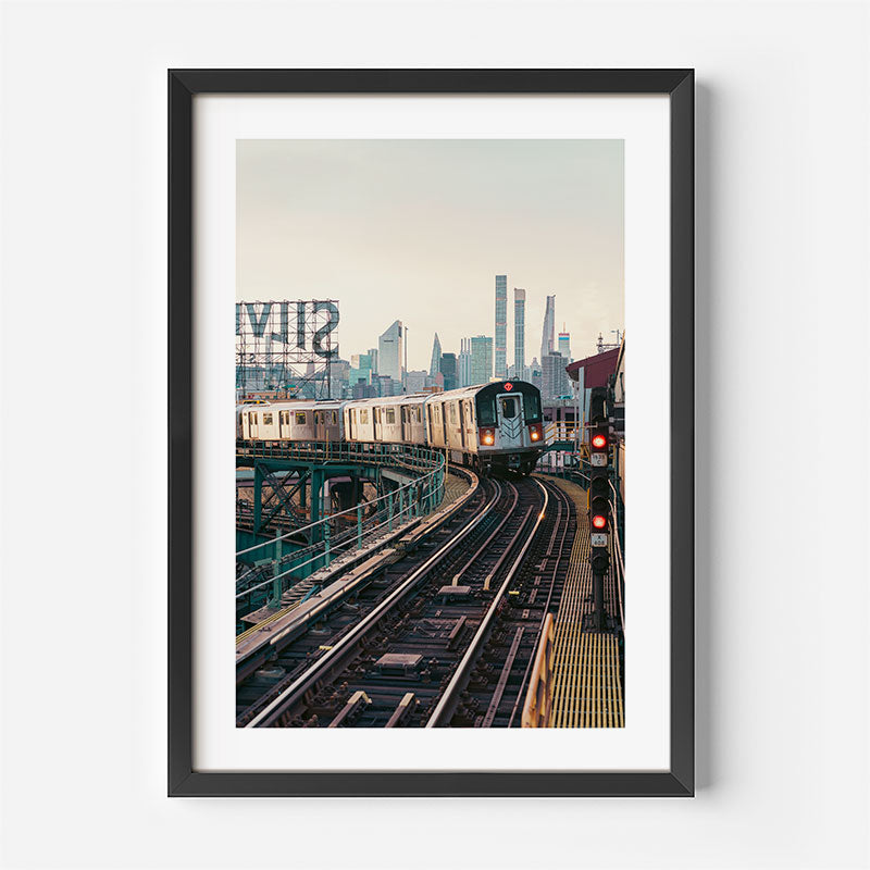 Framed photograph of a train on tracks with city skyline in the background